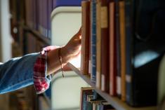 A person reaches for a book in the library